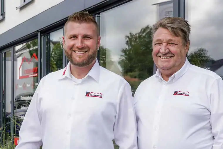 Hans und Marcus Eberhardt in weißen Hemden mit Firmenlogo vor dem Firmengebäude in Ulm-Ermingen
