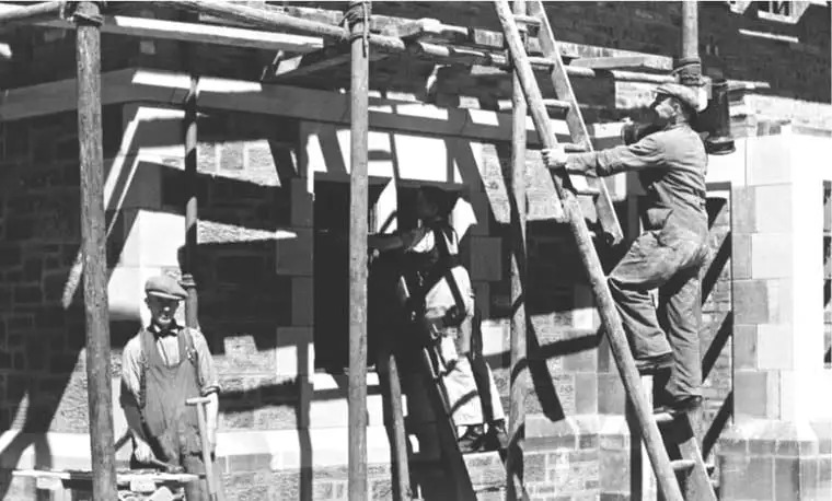 Historische Schwarzweiß-Aufnahme von Maurern bei der Arbeit auf einem Holzgerüst